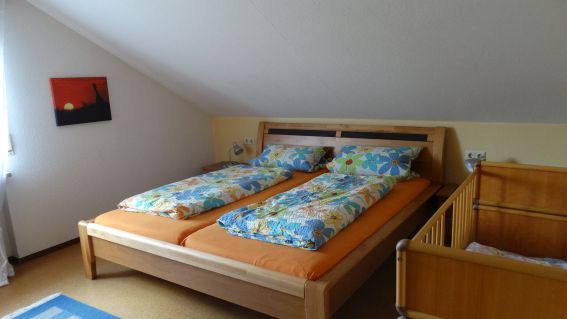 Zweites Schlafzimmer mit Doppelbett und Kinderbett in der Ferienwohnung Kirsche