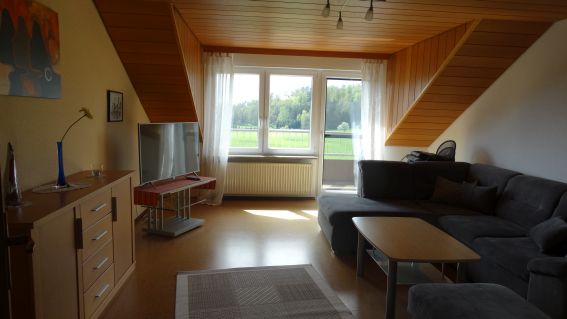 Helles Wohnzimmer der Ferienwohnung Kirsche mit Sofa und Balkontür